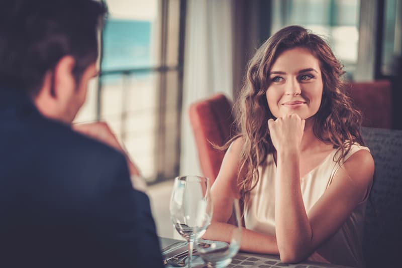 smiling woman looking at man sitting with her in a restaurant