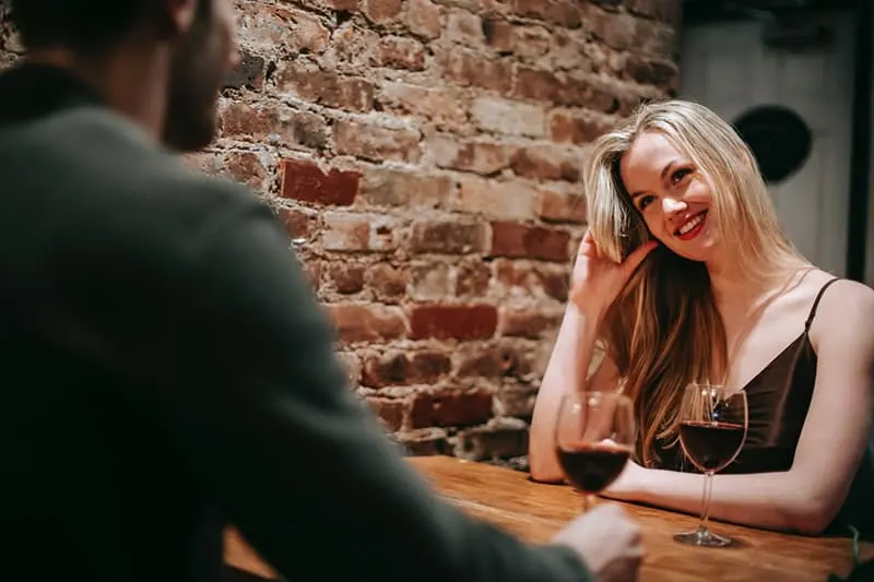 smiling woman sitting with her boyfriend in restaurant celebrating anniversary