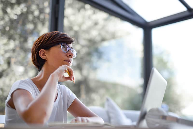 thoughtful woman holding pencil while sitting at the desk