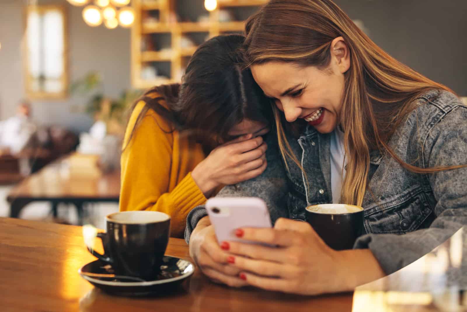 dos amigas sonrientes sentadas a la mesa