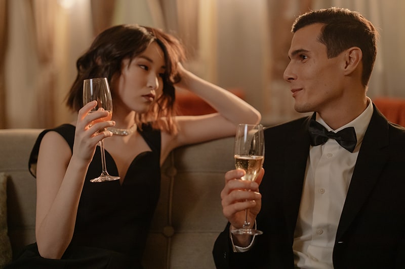 donna e uomo che bevono champagne seduti insieme sul divano