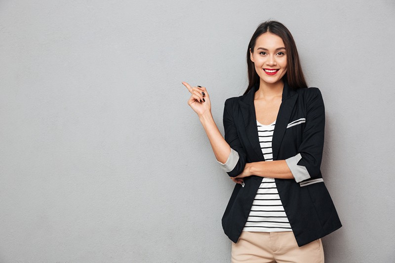 woman in black blazer with index finger pointing up 