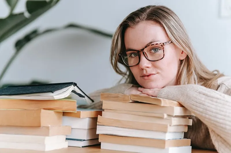 woman leaning on stack of the books while thinking
