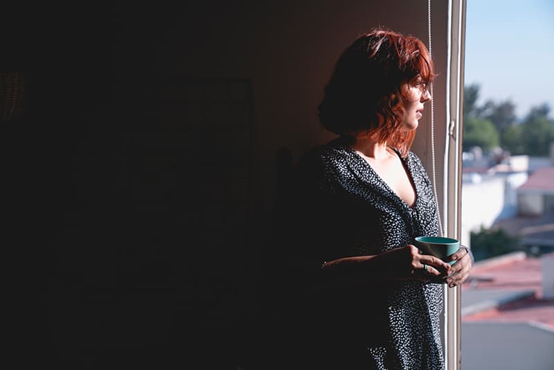 woman looking outside holding a mug