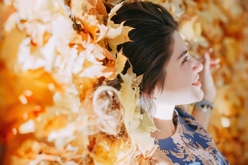 woman lying in dried leaves facing the sun