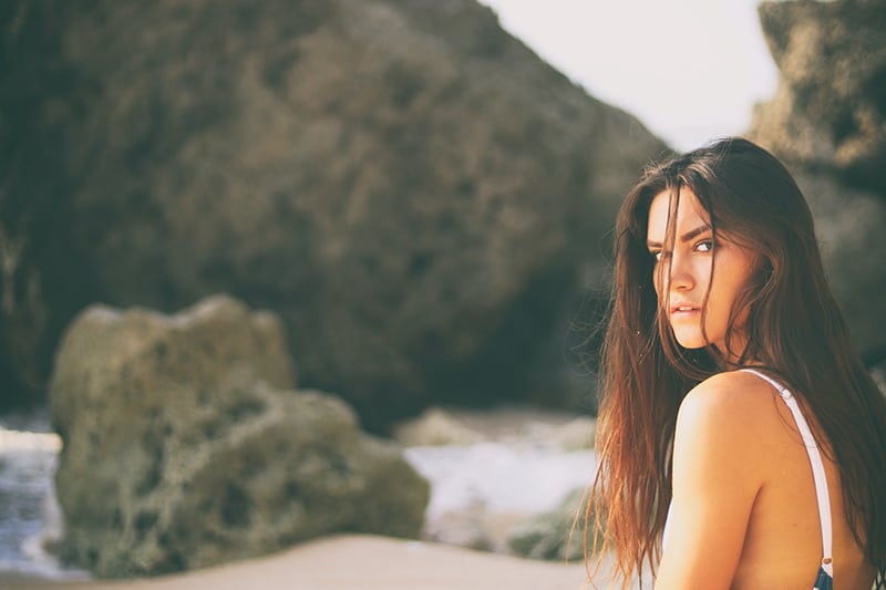 woman sitting on the seashore near the rocks