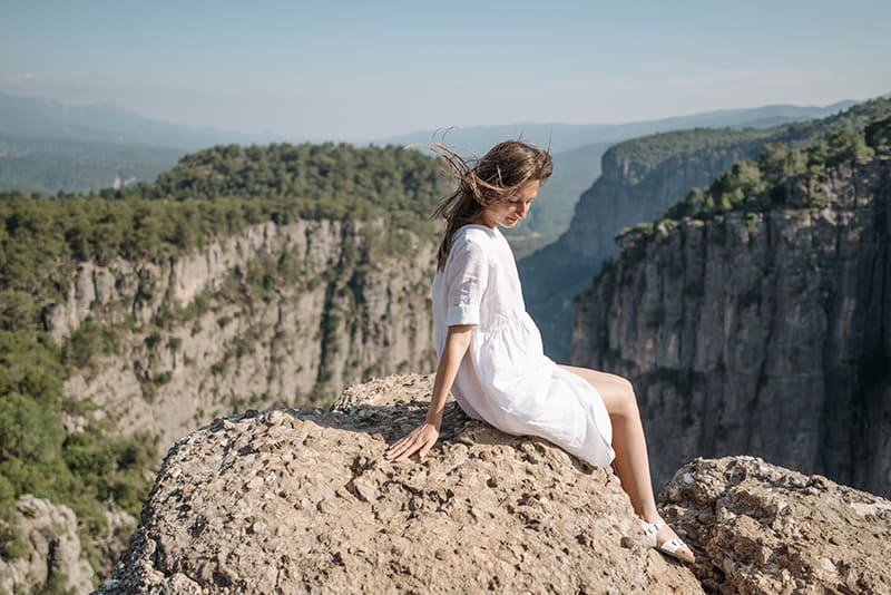donna seduta sulla roccia mentre pensa