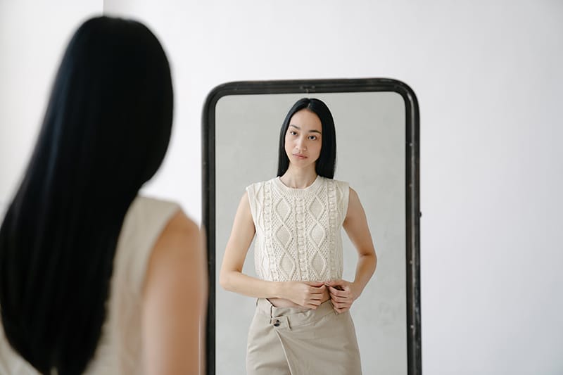 woman standing in front of the mirror and looking herself