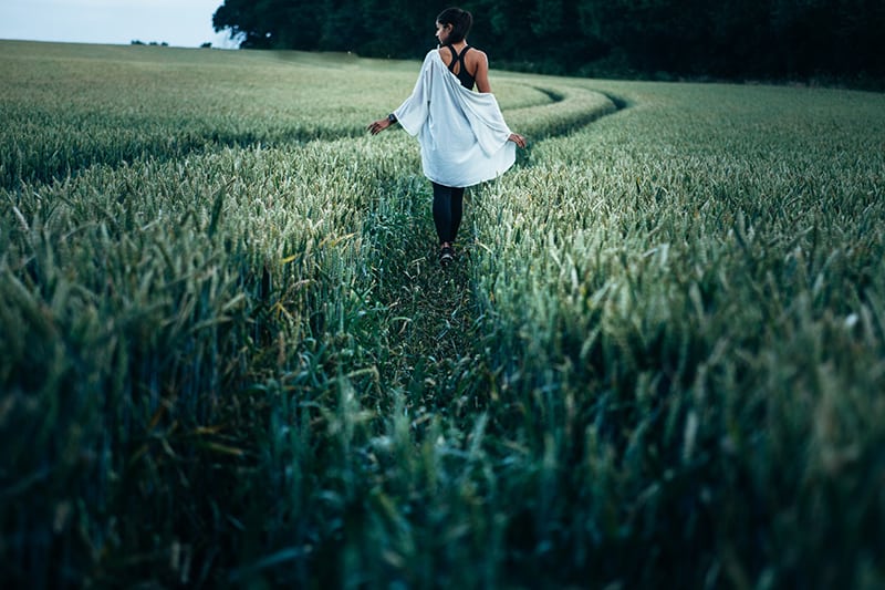 woman walking in the wheat field during daytime