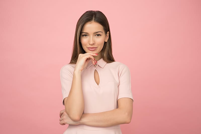 mulher com uma blusa cor-de-rosa a tocar no queixo com a mão