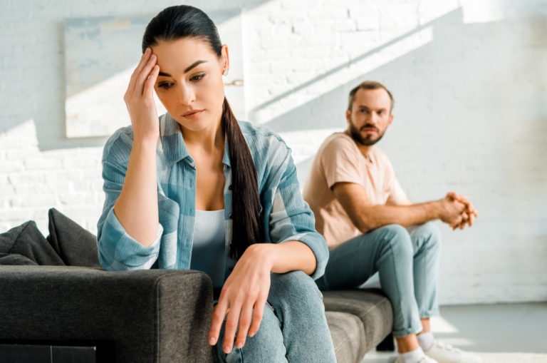 unhappy couple sitting on couch after fight