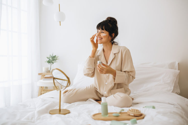woman doing skincare on her bed