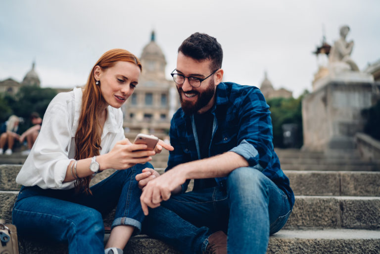 a woman sitting on the stairs with a man and a button on the phone