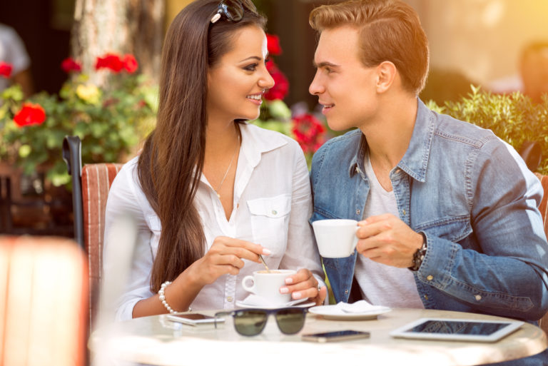 um homem e uma mulher sorridentes a conversar durante um café