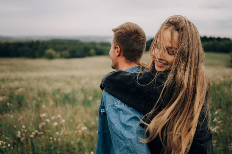 smiling woman hugging man from the back