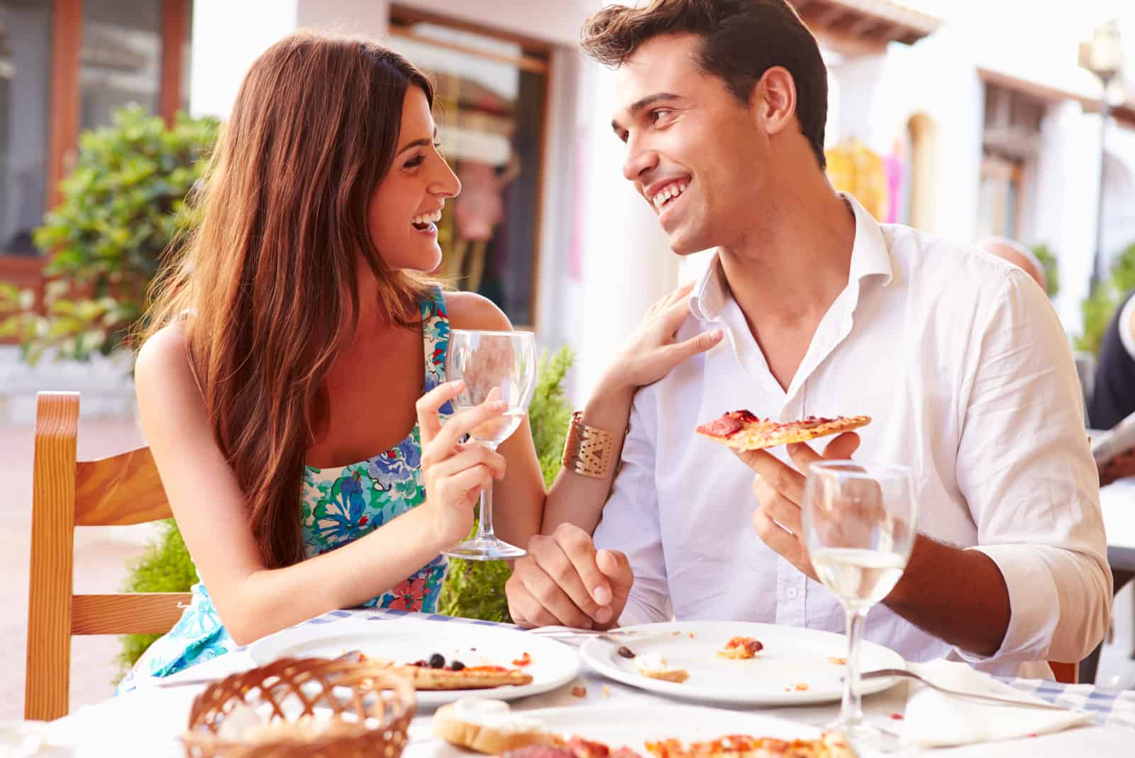 a beautiful couple sitting at a table eating and laughing