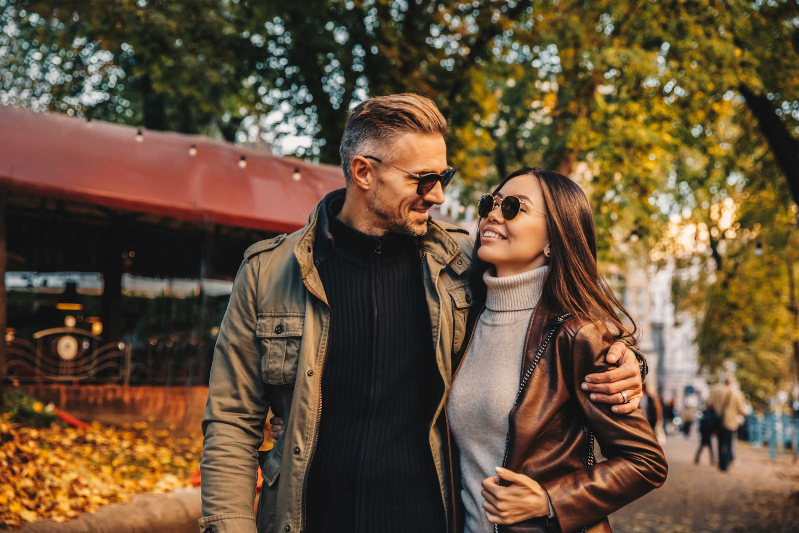 a man and a woman embrace walking through the park