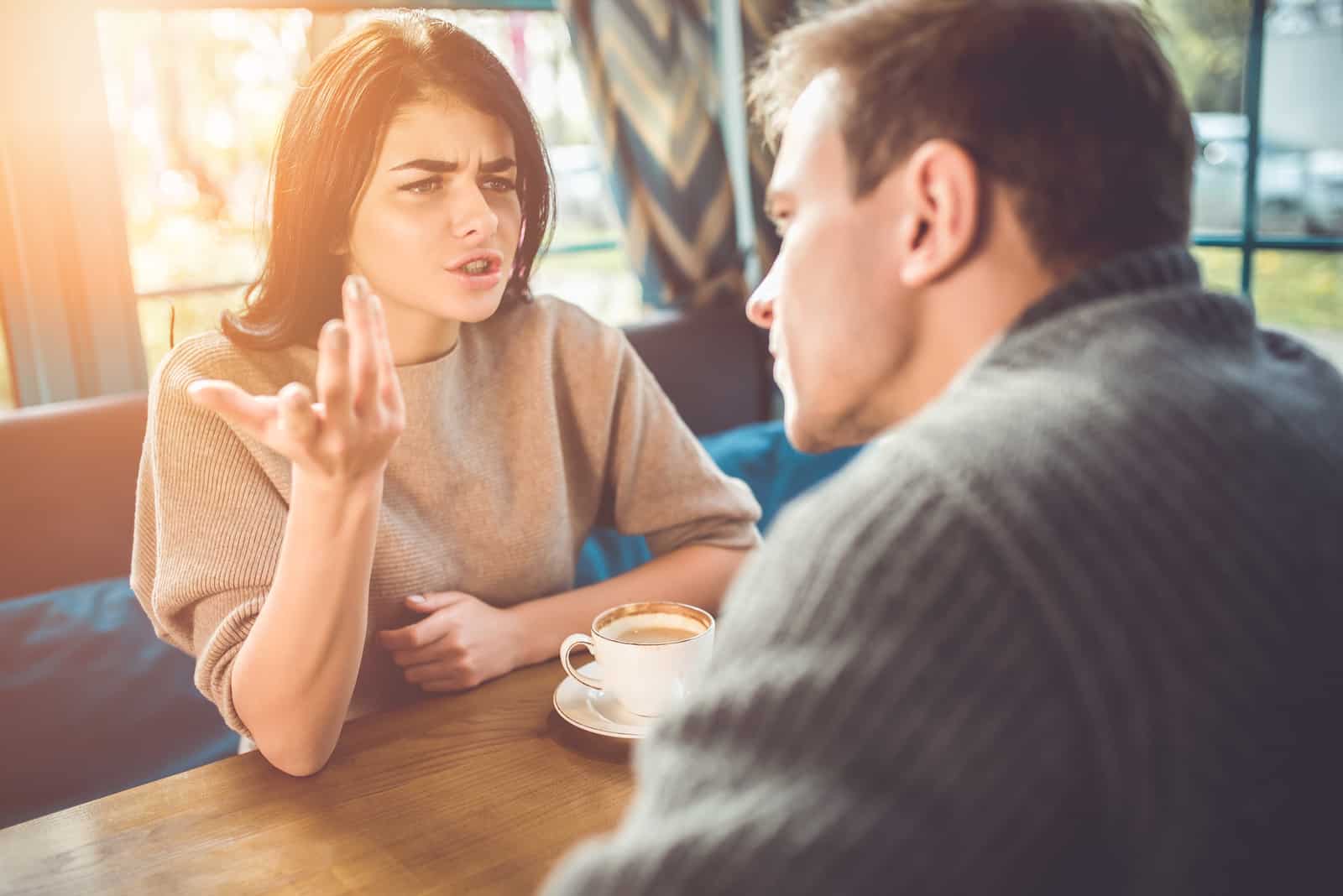 un hombre y una mujer discuten en una cafetería mientras toman café