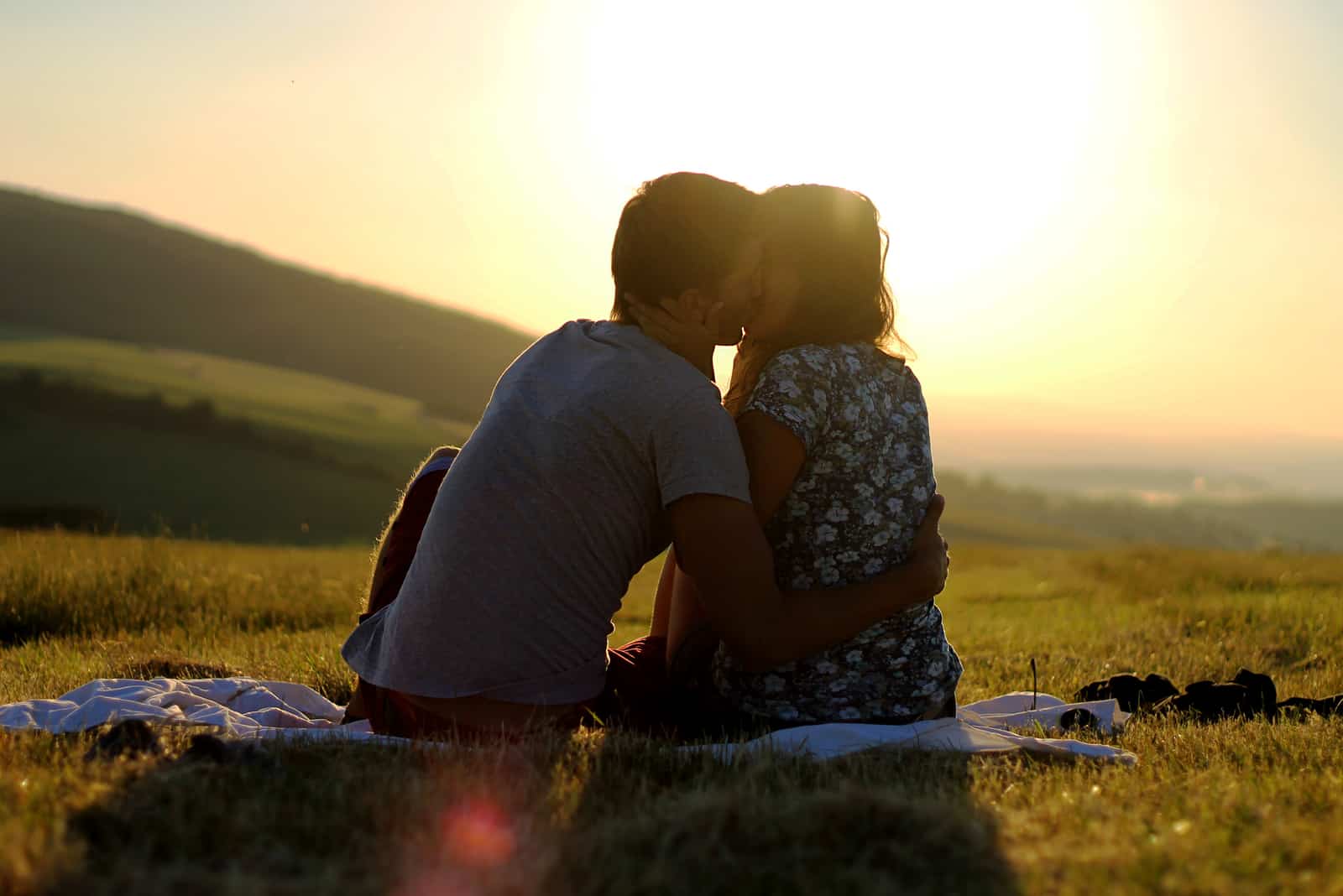 a man and a woman sit on the grass and kiss