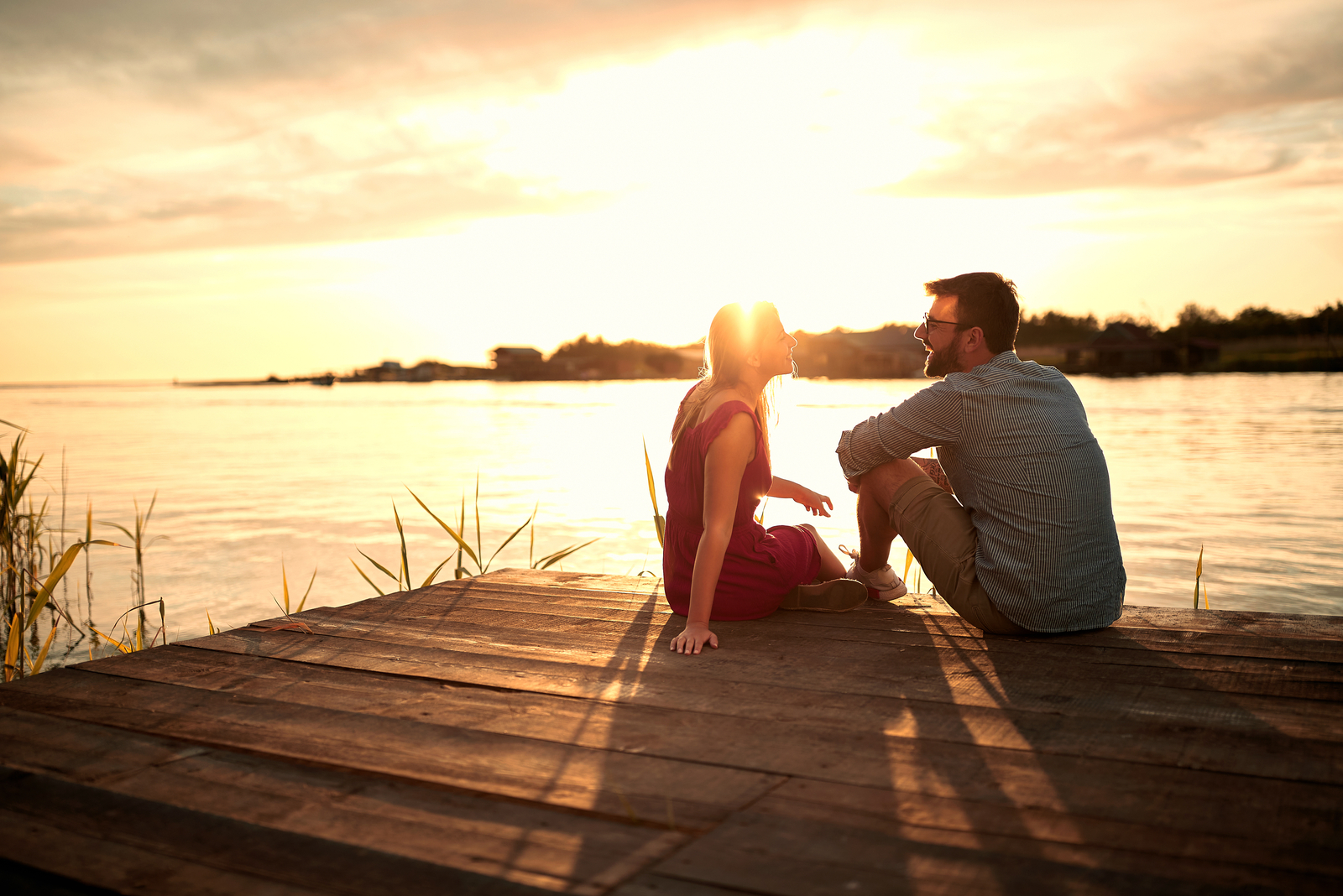 a man and a woman sit on the pier and talk