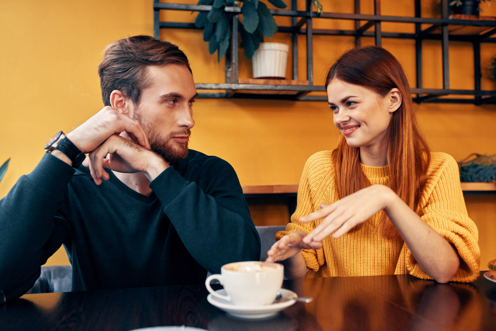 a man and a woman sitting at a table having coffee talking