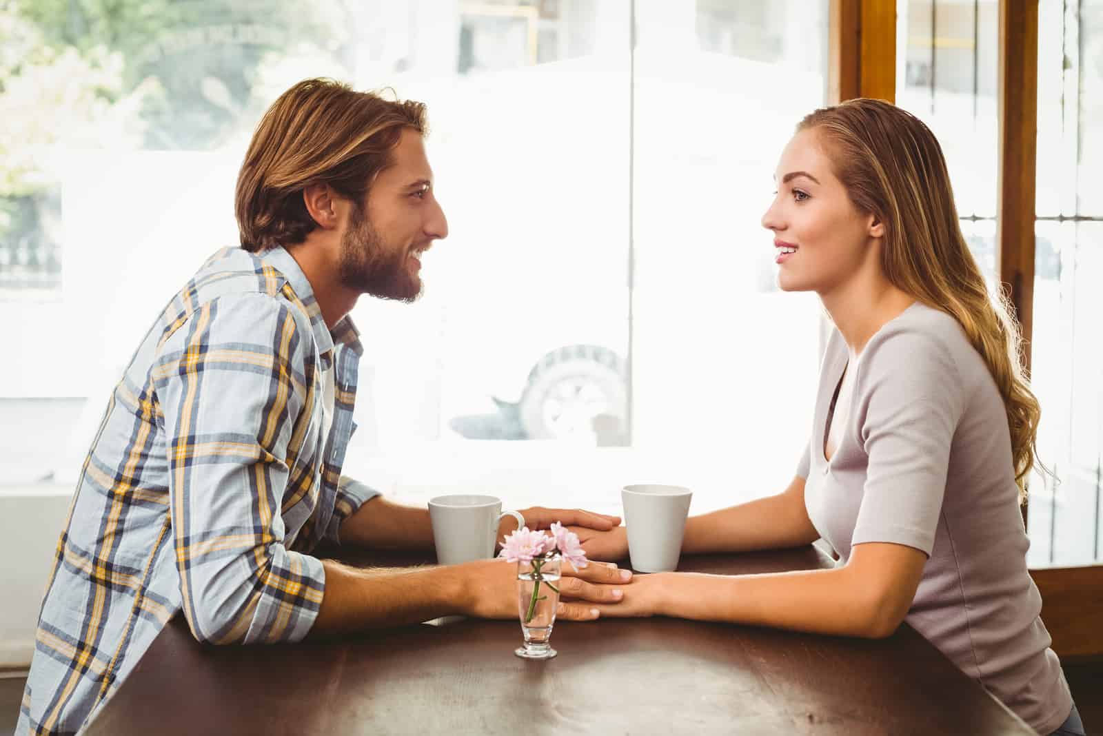 un uomo e una donna seduti a un tavolo che si tengono per mano e parlano