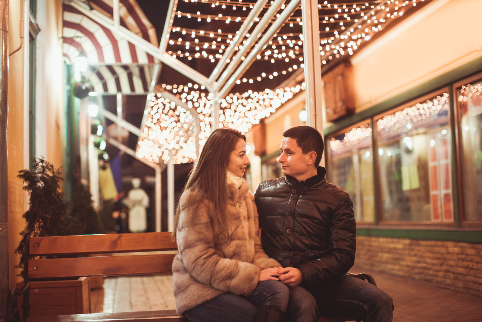 a man and a woman sitting on a bench holding hands and talking