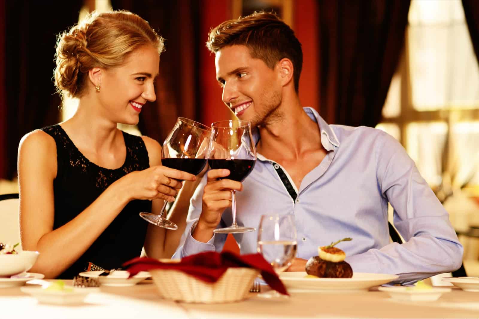 a man and a woman toast with wine as they look at each other