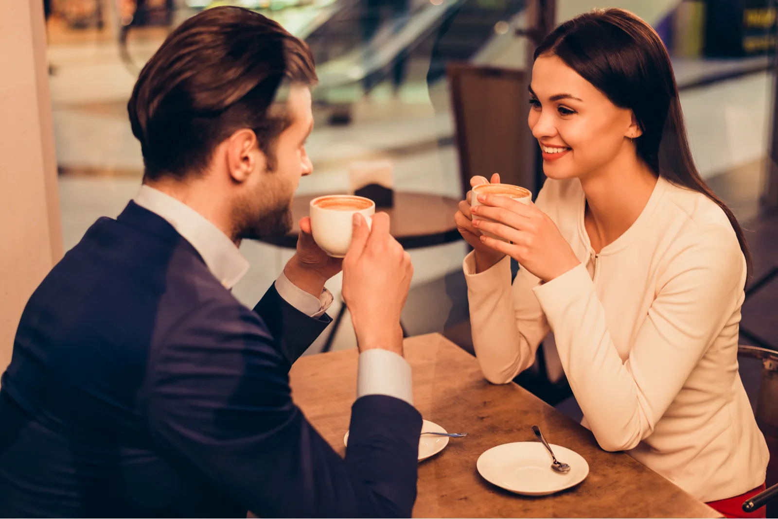 a smiling loving couple sitting at a table drinking coffee