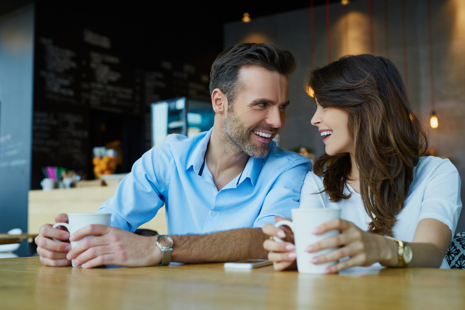 a smiling man and woman sit at a table and talk