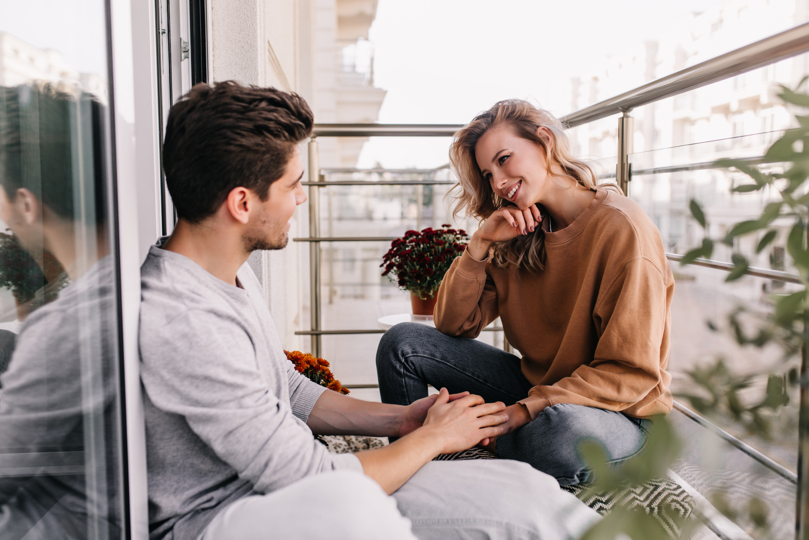 a smiling man and woman sit on the balcony and talk