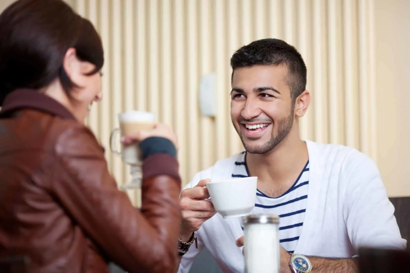 a smiling man and woman talking over coffee