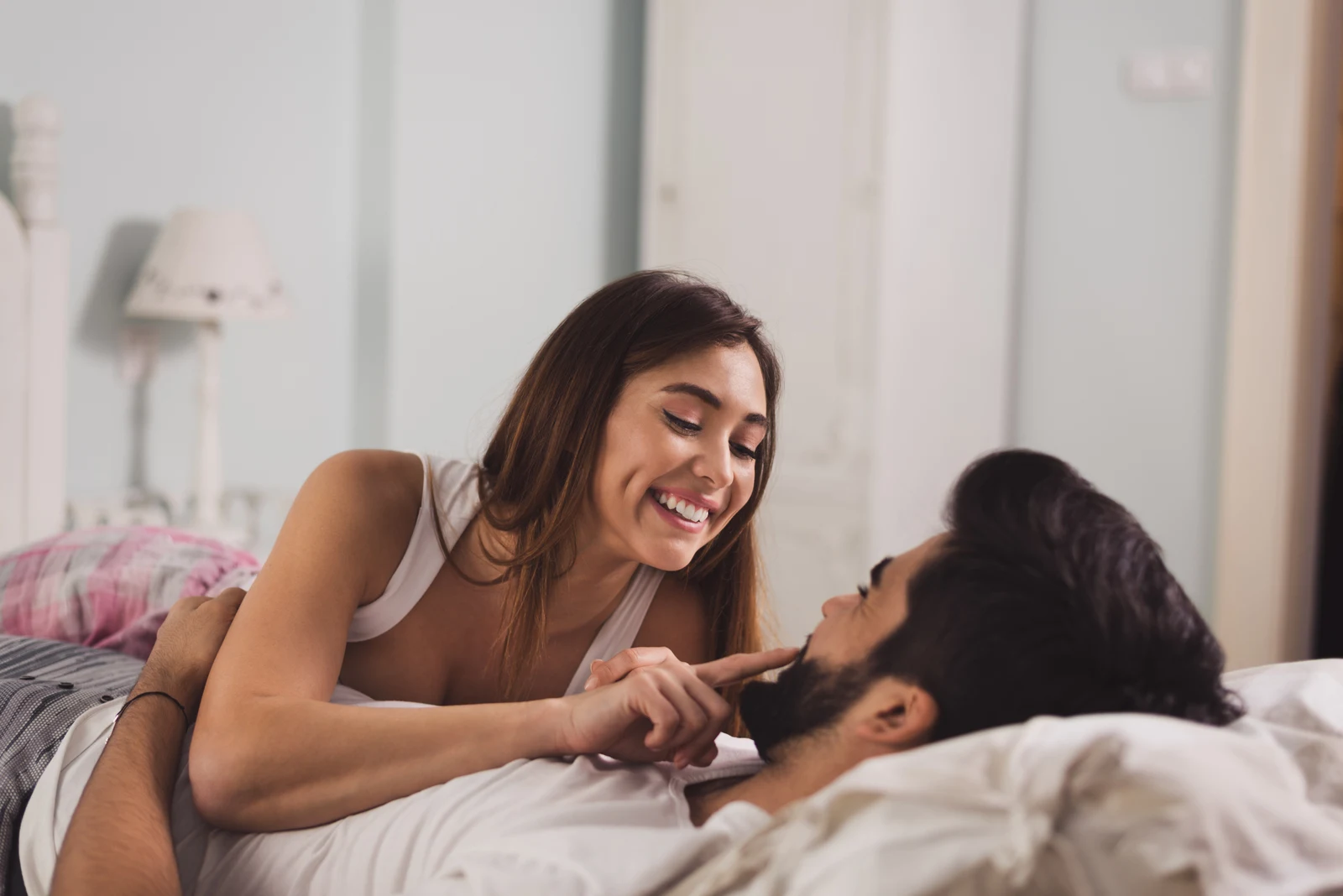 a smiling woman cuddles with a man in bed