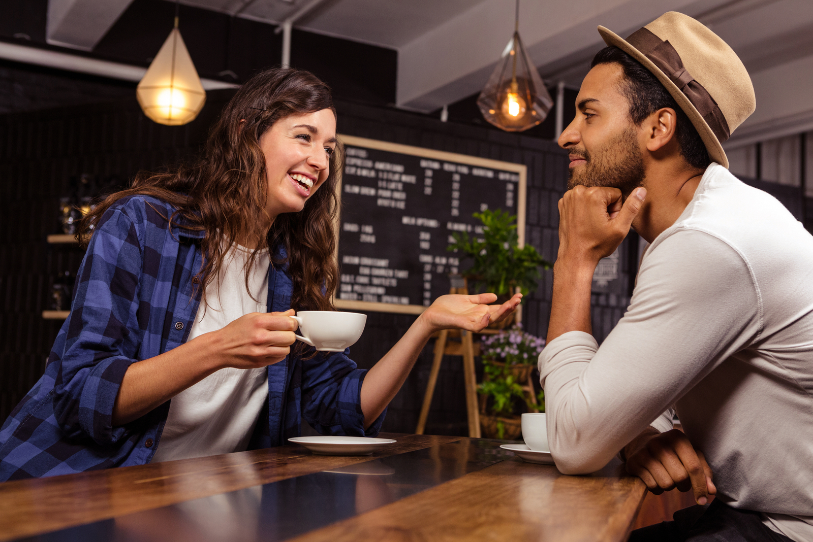 uma mulher sorridente a segurar uma chávena de café e a falar com um homem