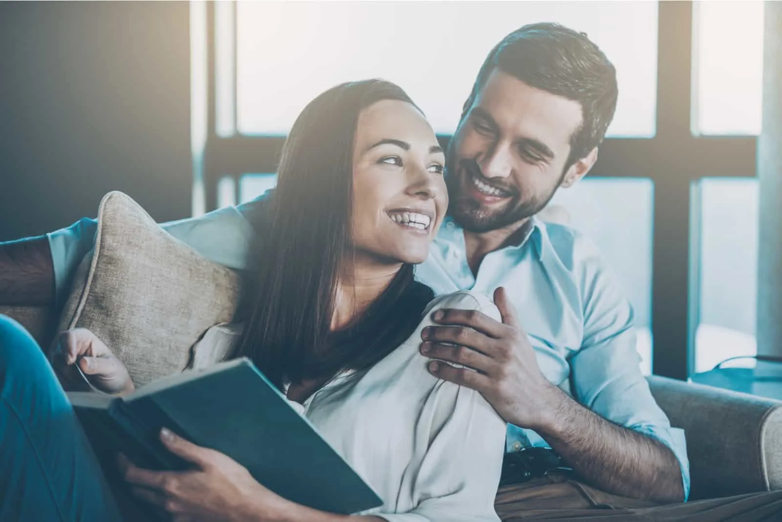 a smiling woman reading a book a man hugged