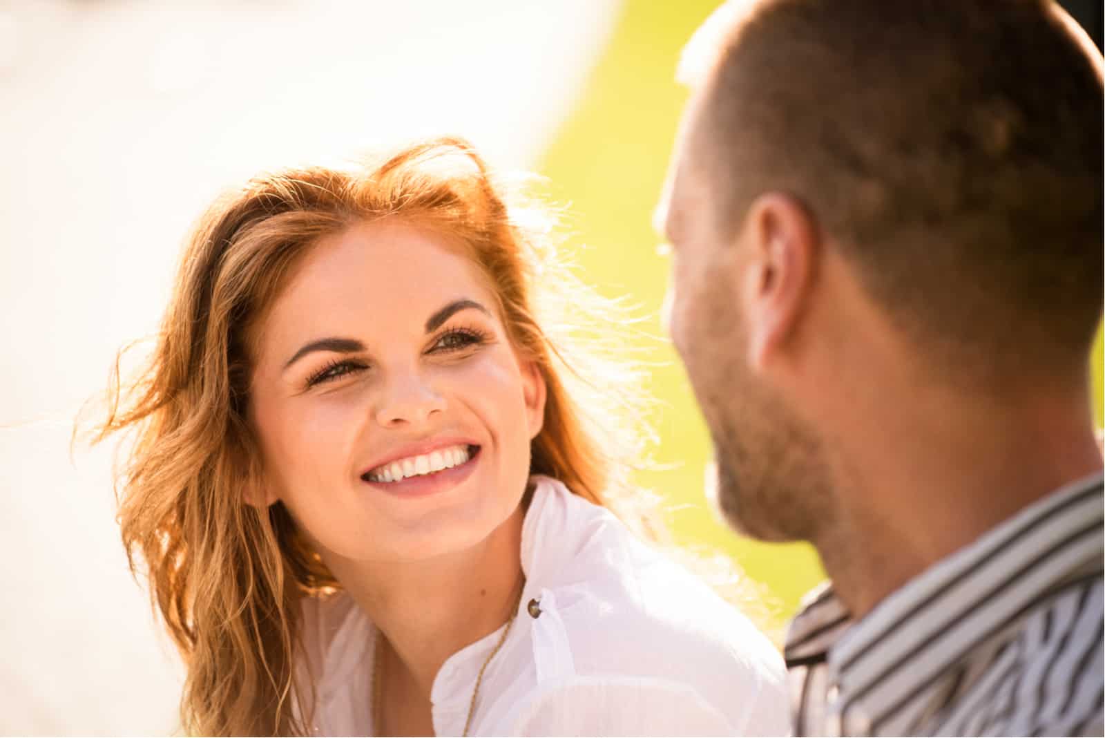 a smiling woman talking to a man