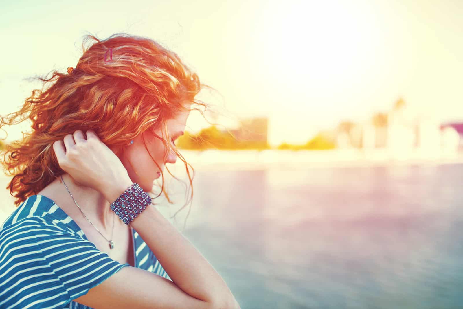 a woman with frizzy hair stands with her head down