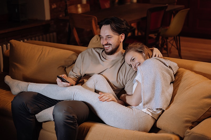 alegre pareja sentada en el sofá por la noche en casa