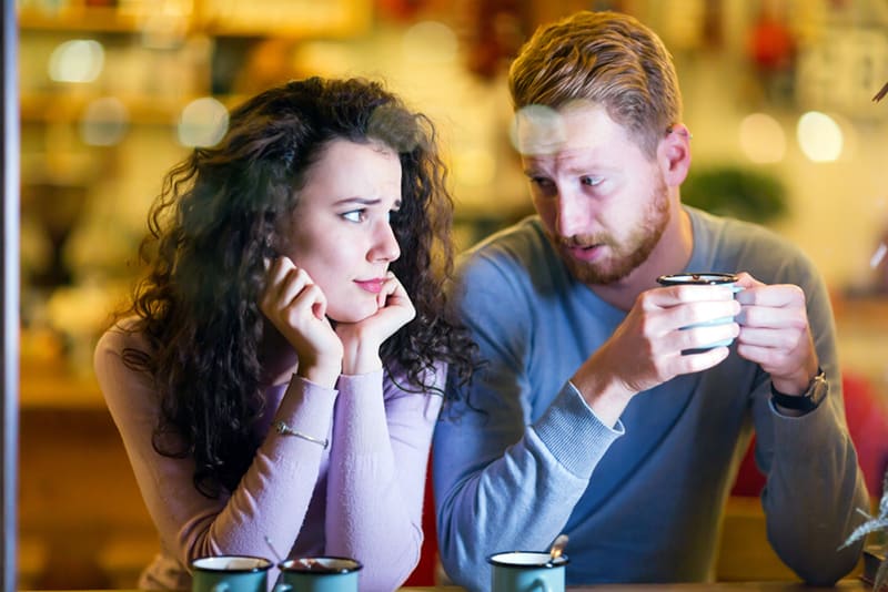 confused woman looking at man talking to her in the cafe