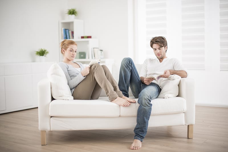 pareja leyendo un libro en el sofá de casa