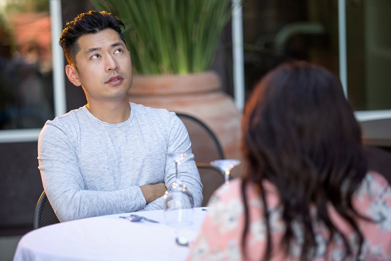 disappointed man sitting with a woman on a date in the restaurant