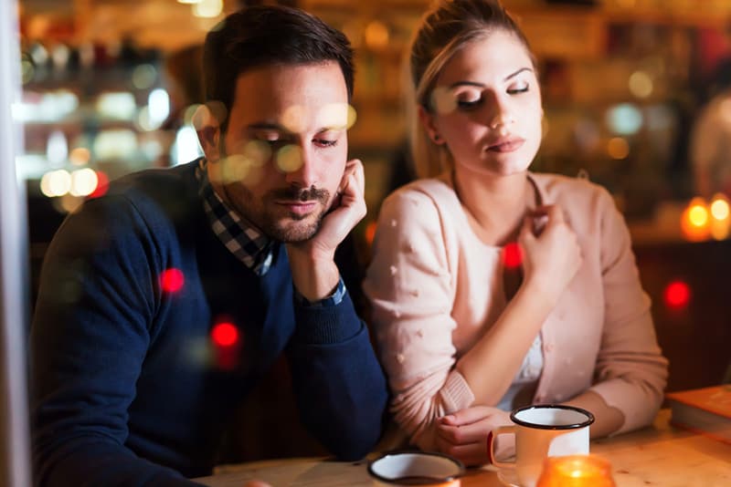 pensive couple sitting in the cafe without talking