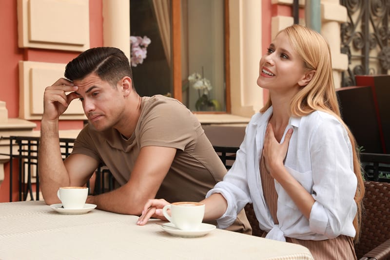 uomo pensieroso che ha un appuntamento con una donna loquace nel caffè