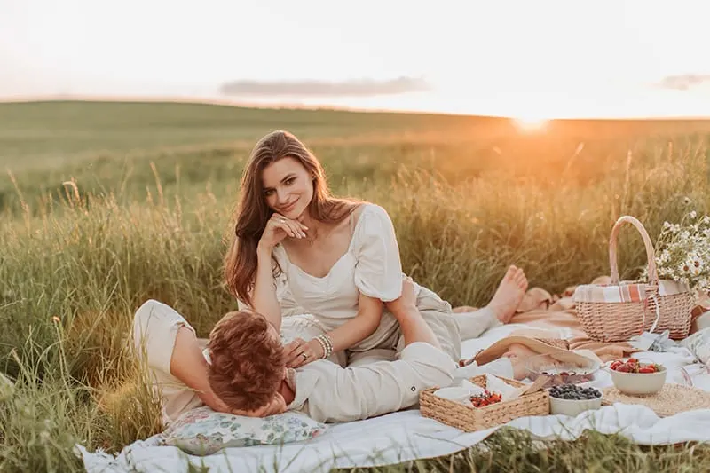 romantic couple sitting in the field on picnic during sun set