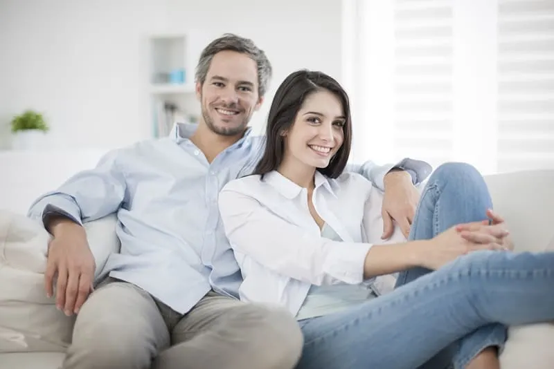 smiling couple sitting on the couch at home