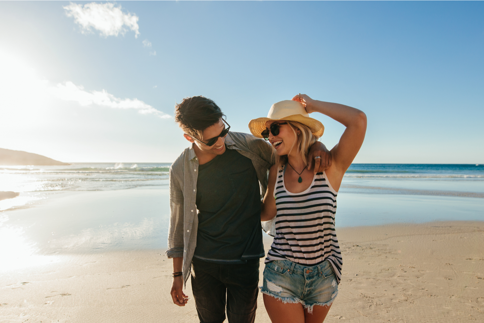 smiling loving couple embracing walking along the beach