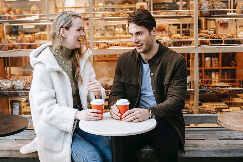 smiling man and woman talking in cafe outdoors