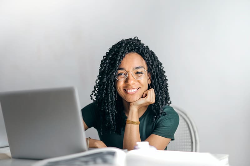 donna sorridente seduta alla scrivania davanti al computer portatile