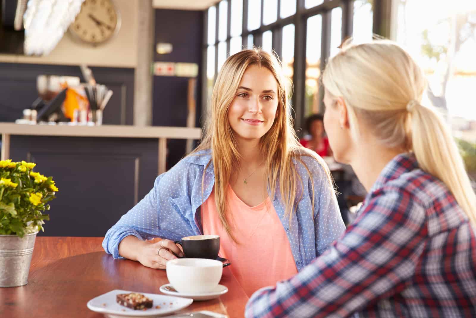 dos amigos están sentados en una mesa tomando café hablando