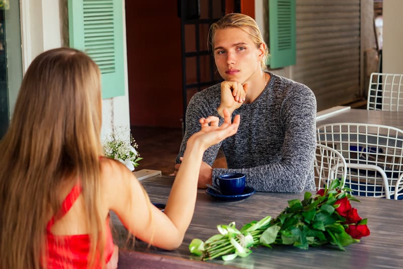upset man sitting with a woman on a date in the cafe